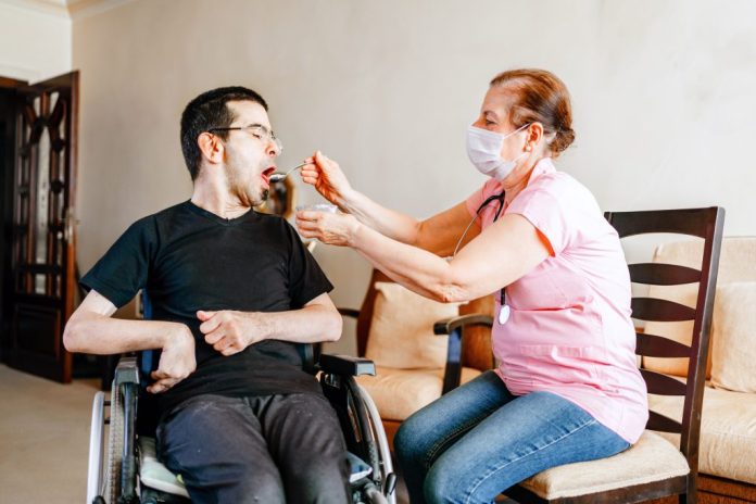 A caregiver feeds a disabled man in a wheelchair. (Photo by Getty Images)