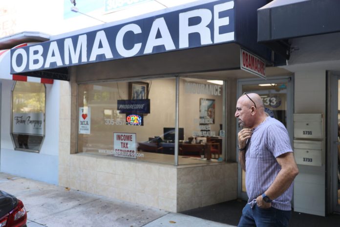 The owner of an insurance agency that offers Obamacare plans stands outside his storefront in Miami, Fla, in 2021. In 49 states, the number of people enrolled in Obamacare plans has declined. (Photo by Joe Raedle/Getty Images)