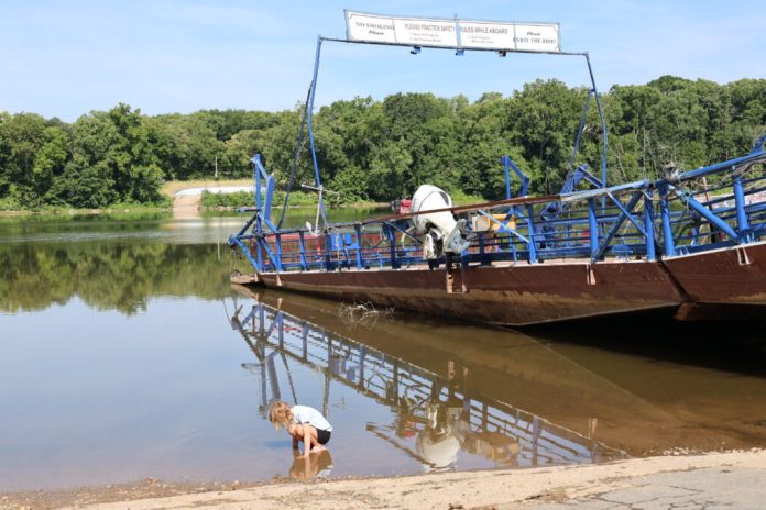 A child plays in the water next to the White’s Ferry vessel in the Potomac River across from Loudoun County in Virginia. (Photo by Nathaniel Cline/Virginia Mercury)