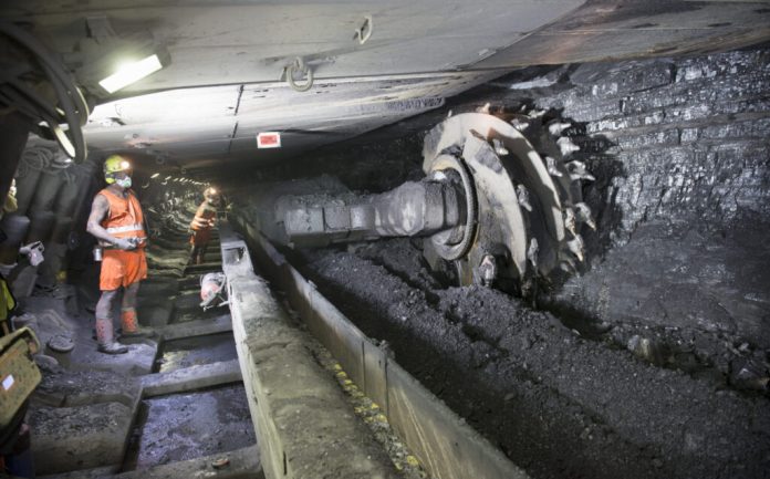 Coal miners working underground with heavy machinery in a mine
